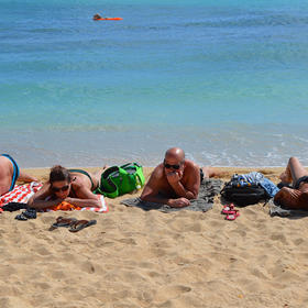 《晒日光浴的游客》在美国夏威夷的海滨，几个游客自由...