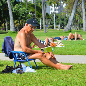 在美国夏威夷海滨公园，一个老年人光着上身坐在椅子上...