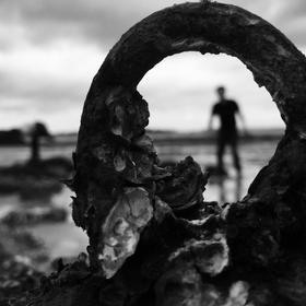       海边游玩，礁石上布满牡蛎壳。偶然发现一个铁环...