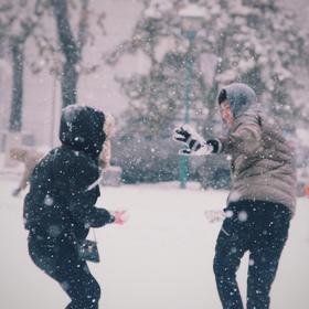 摄于雪中的大学校园，年轻的情侣在雪中忘我地玩扔雪球...