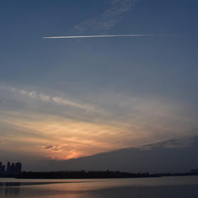 在湖边拍的夕阳，正好遇见天上有飞机拖着白色的尾巴飞...
