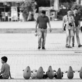 艾提尕尔清真寺广场上人来人往，一位买小企鹅玩具的小...