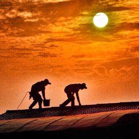 《阳光伙伴》黄昏时，天台上工作的两名工人。...