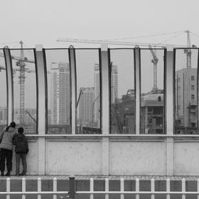 取景：正在建设的新哈尔滨站，一对母子从桥上望向正在...