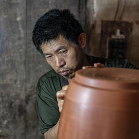 取景：在云南建水县，一名制陶人正在专心的雕磨陶罐
...