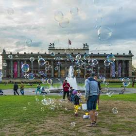 在柏林大教堂的广场上，大人陪着小孩正在追逐着泡泡玩...