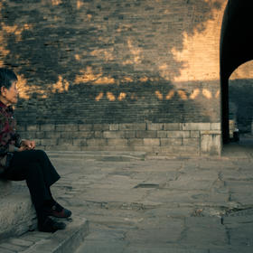取景： 平遥古城内，一老妇静静坐着，望向城门，似在等...