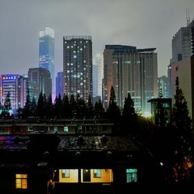 寒潮来袭前的南京，远处的冷光大厦与近处的暖光居民楼...