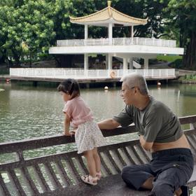 公园里爷爷告诉孙女湖里有鱼，孙女好奇的寻找，路过拍...