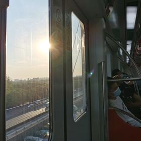 清晨，阳光穿过车窗洒进地铁车厢里，车上的人有的还在...