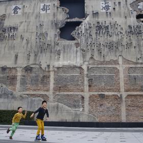 背景是上海四行仓库，墙上的弹孔和残破记录着当年八百...