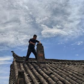 《修屋顶的工人》丽江玉湖古村一个老建筑屋顶上，手机...
